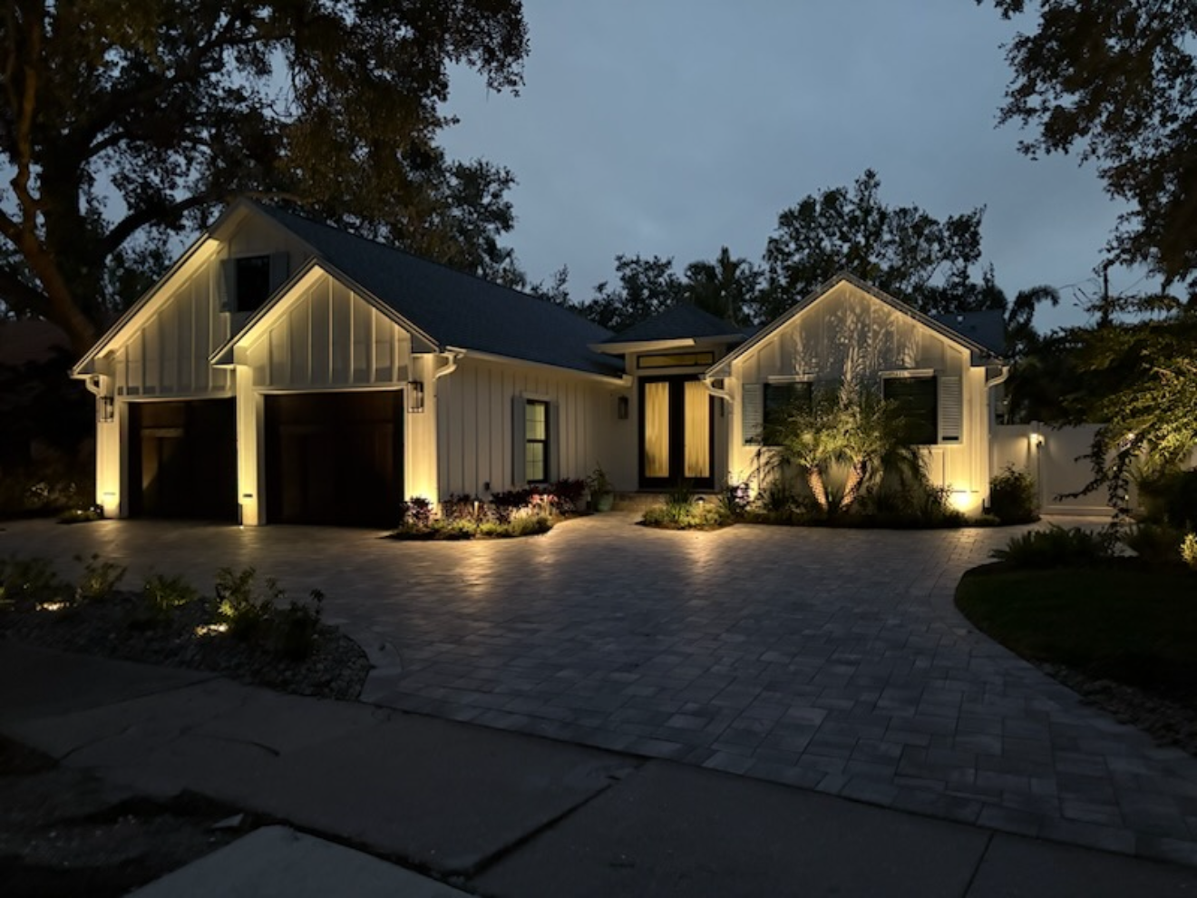 Modern farmhouse with driveway and uplighting